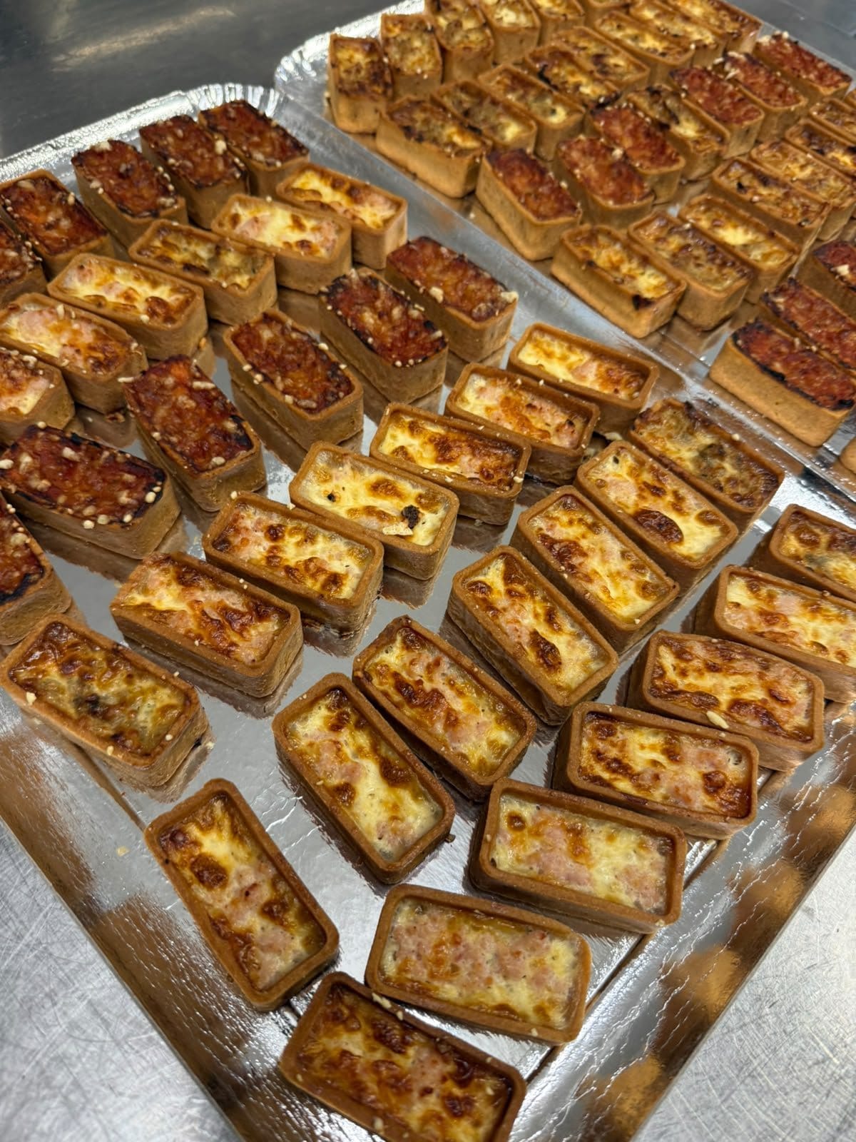 Plateaux de mini tartelettes apéritives gratinées, tout juste sorties du four du laboratoire
