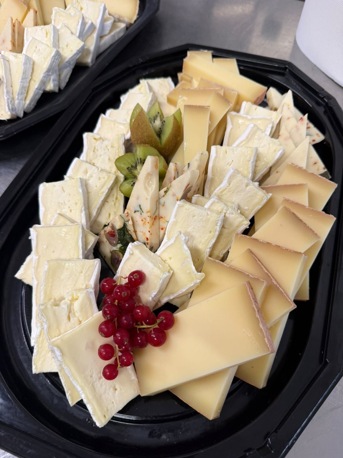 Plateau de fromages préparé par la maison : brie, tomme, fromage aux épices, groseilles et kiwi