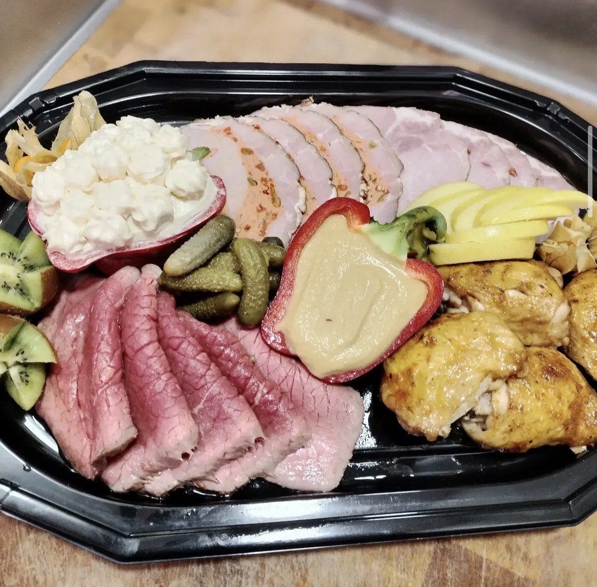 Plateau traiteur garni de rôti, jambon, viande des Grisons, poulet doré, cornichons et fruits frais