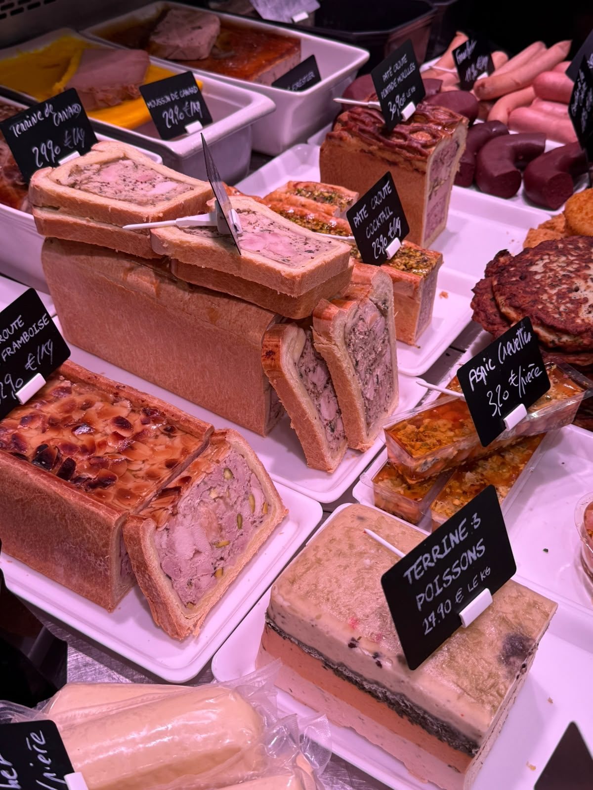 Pâtés en croûte et terrines de la maison en vitrine, dont un pâté en croûte aux pistaches et amandes